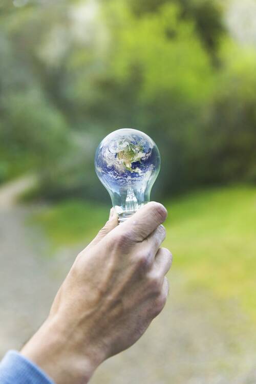 Adult arm keeping lamp with planet
